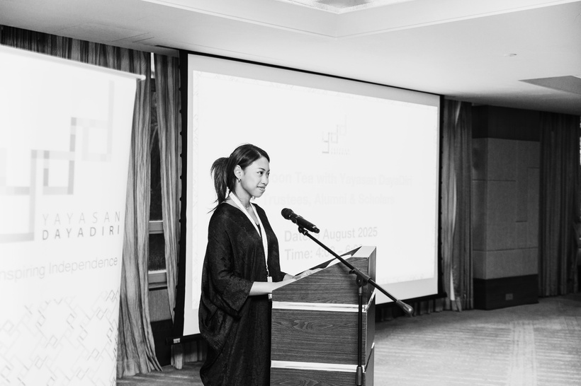 Deha speaking at a lectern in front of YDD alumni