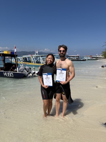 Michael and Deha holding their scuba certification cards