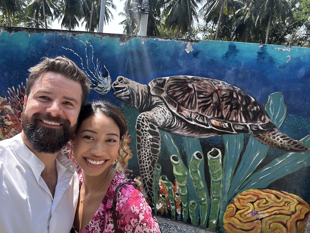 Michael and Deha taking a selfie beside a sea-turtle mural